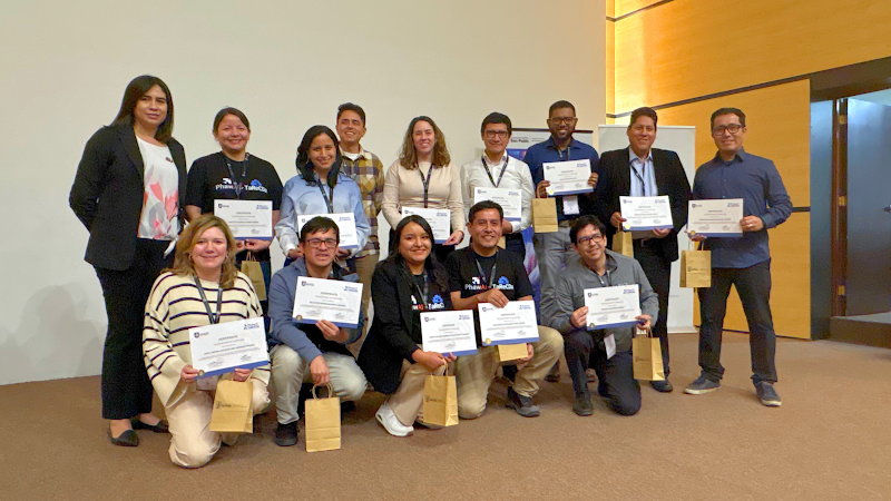 A group of 14 people from the event posing for a photograph. All except two are holding up certificates.