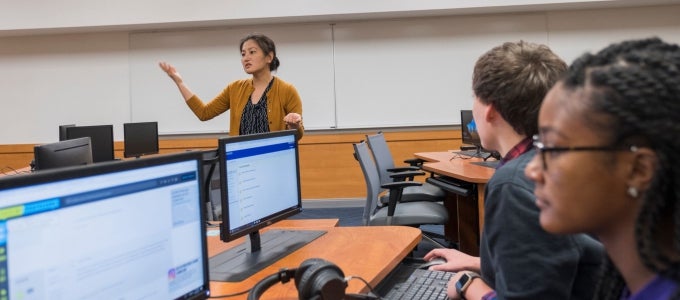 female professor teaching to students looking at computer screen