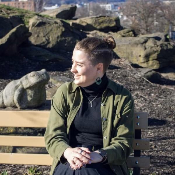 Lynn Priestley sitting on a bench outside in front of large rocks