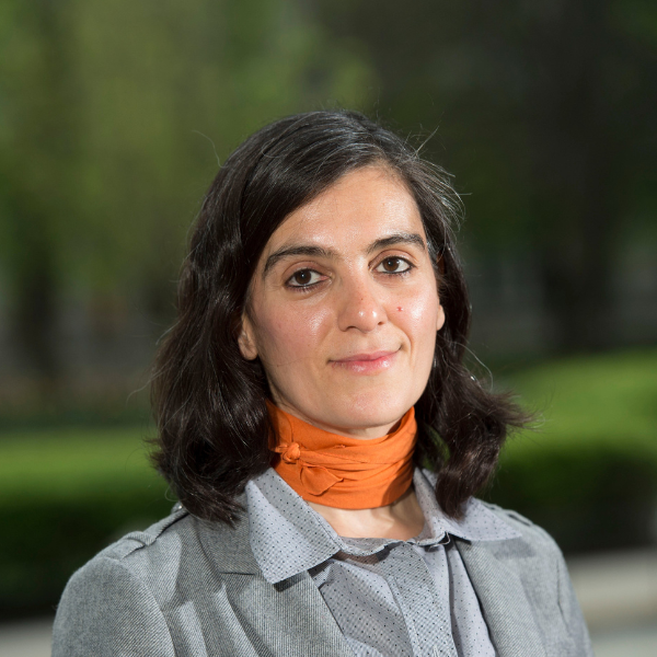 woman with dark hair wearing orange scarf and gray outfit