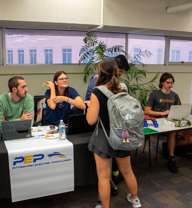 girl wearing backpack talking to people at an informational table