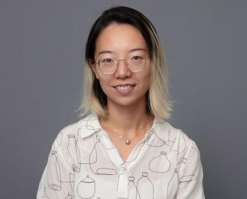 Photo of a woman in a blouse sitting in front of a gray backdrop