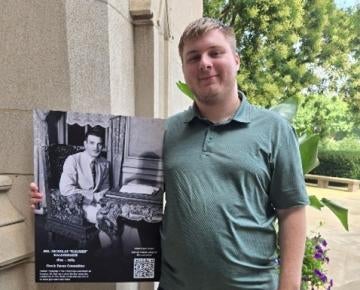Photo of Aidan Brophy standing next to a sign outside