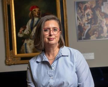 woman wearing long sleeved shirt standing in front of paintings