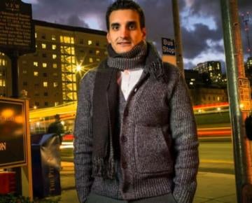 man wearing gray sweater and scarf outside at night