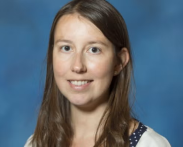 woman with long brown hair in front of blue backdrop