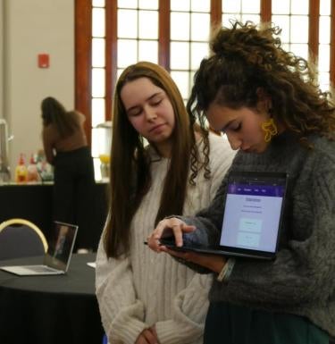 Two female students present with a laptop