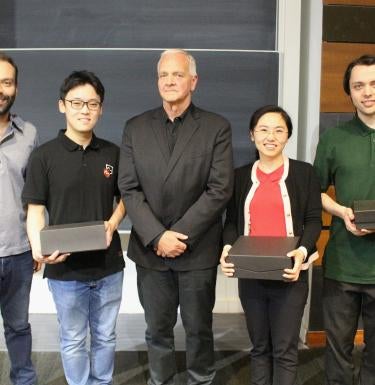 Photo of Four People Posing with Two Holding Plaques