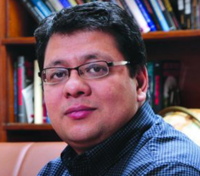 Photo of James Joshi in front of bookshelf