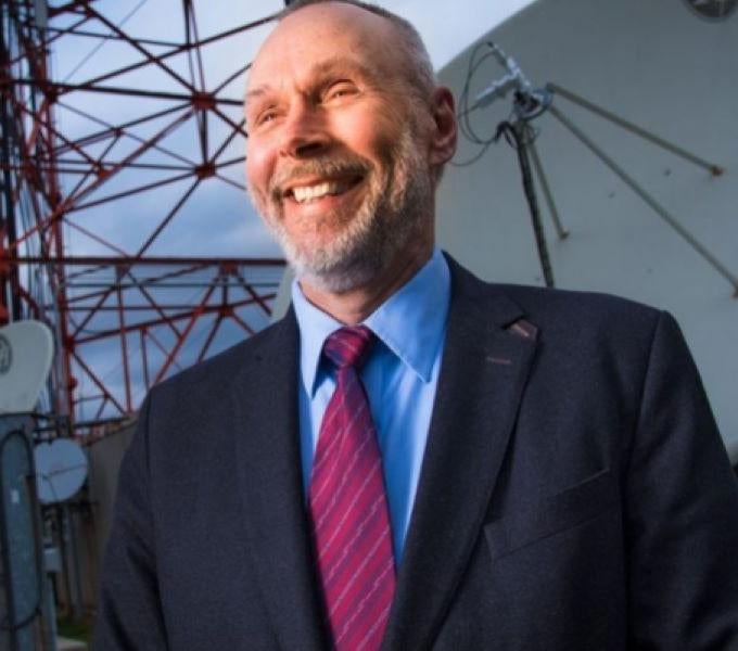 Photo of Martin Weiss in front of a satellite 
