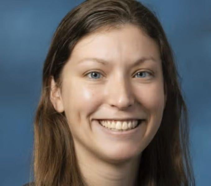 woman with long brown hair in front of blue backdrop