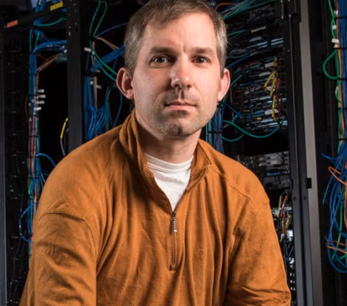 man wearing orange shirt in front of servers