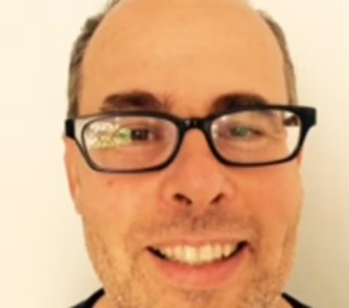 man wearing glasses in front of a white wall