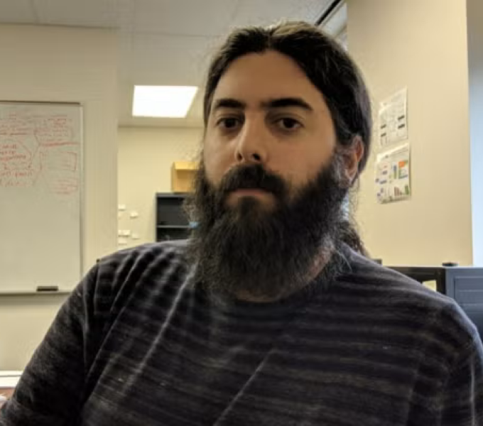 man with beard sitting at a desk