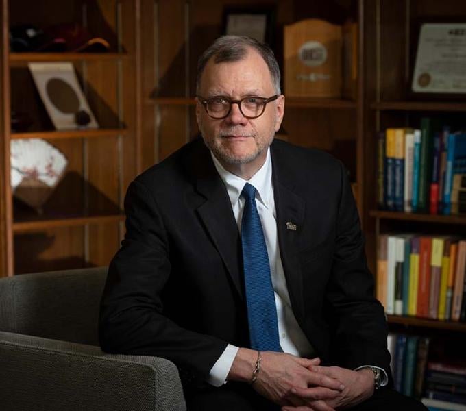 man in suit sitting on a chair in a study